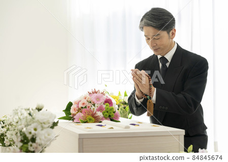 A man in mourning with a bead in front of a casket A man in mourning with a bead in front of a casket 84845674