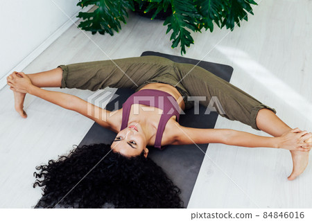 woman brunette doing exercises yoga asana gymnastics in white hall woman brunette doing exercises yoga asana gymnastics in white hall 84846016