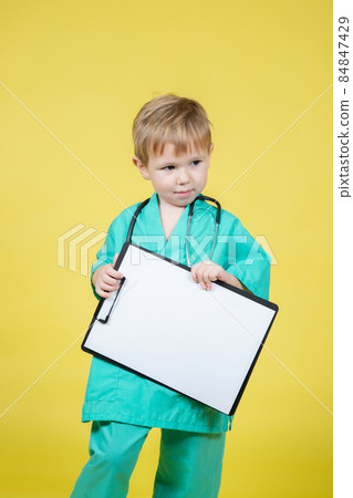 Portrait of little kid dressed in doctors green coat holds tablet in hand Portrait of little kid dressed in doctors green coat holds tablet in hand 84847429