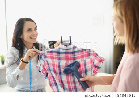 Girls atelier coworkers use clothing steamer on shirt, prepare for selling Girls atelier coworkers use clothing steamer on shirt, prepare for selling 84847613