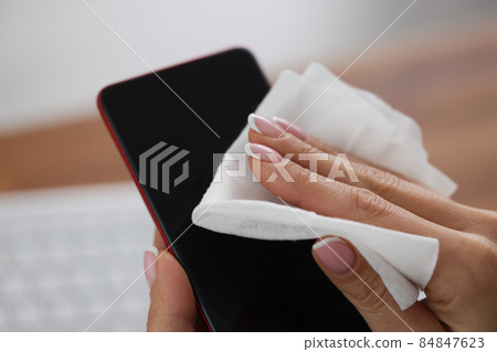 Woman clean mobile phone screen with wet wipe, antibacterial and disinfecting procedure 84847623