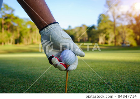 Hand hold golf ball with tee on course, golf course background. Hand hold golf ball with tee on course, golf course background. 84847714