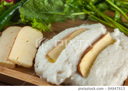 Mengrelian corn mamalica (ghomi) with cheese and various herb on wooden table. Georgian traditional food Mengrelian corn mamalica (ghomi) with cheese and various herb on wooden table. Georgian traditional food 84847813