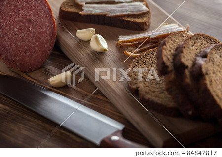 bacon and sausage with black bread and garlic on a wooden table 84847817
