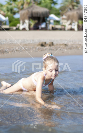 Little girl playing on the beach by the sea 84847893