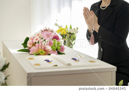 Funeral image: A woman holding a bead in front of a casket Funeral image: A woman holding a bead in front of a casket 84848345