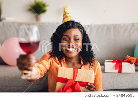 Black Woman Celebrating Birthday Toasting To Camera Holding Gift Indoor Black Woman Celebrating Birthday Toasting To Camera Holding Gift Indoor 84849593