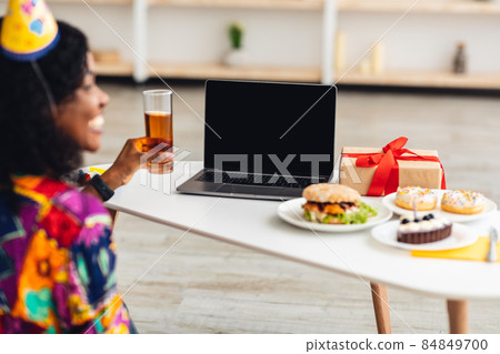 African Female In Festive Hat At Laptop Screen Indoor, Back-View African Female In Festive Hat At Laptop Screen Indoor, Back-View 84849700