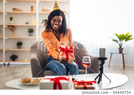 African Female Showing Gift To Smartphone Celebrating Birthday Online Indoors African Female Showing Gift To Smartphone Celebrating Birthday Online Indoors 84849754