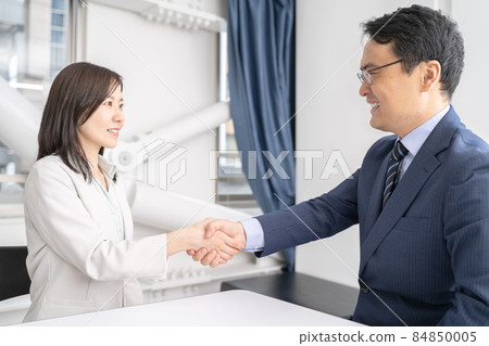 Male and female businessmen shaking hands in the office 84850005