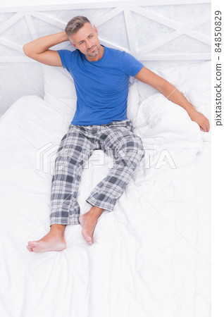 Happy guy in cozy pyjamas daydream resting in bed in morning, daydreaming 84850829