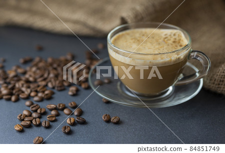 hot delicious aromatic cappuccino coffee in a glass transparent cup on a background of coffee beans 84851749