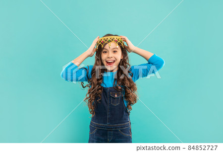 laughing child with curly hair in queen crown on blue background, happiness 84852727