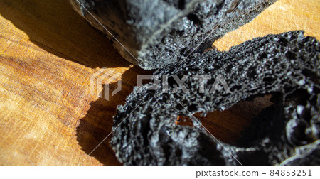 Black bread on a plank and black table. Above view of healthy bread. Strange food. Halloween bread buns. Black bread on a plank and black table. Above view of healthy bread. Strange food. Halloween bread buns. 84853251