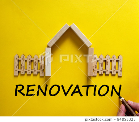 Hand writing 'renovation' on beautiful yellow background. Model of a wooden house. Male hand, wooden fence. Copy space. Business concept. Hand writing 'renovation' on beautiful yellow background. Model of a wooden house. Male hand, wooden fence. Copy space. Business concept. 84853323