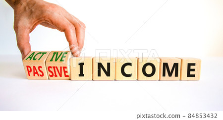 Passive or active income symbol. Businessman turns wooden cubes and changes words passive income to active income. Beautiful white background, copy space. Business, passive or active income concept. 84853432