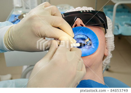 Patient getting dental treatment at dentist office with dental rubber dam protection Patient getting dental treatment at dentist office with dental rubber dam protection 84853749
