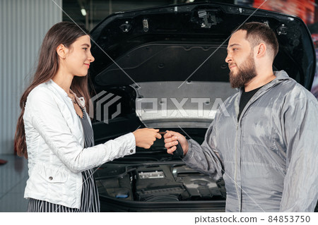 Man giving client keys to her repaired car in auto repair service 84853750
