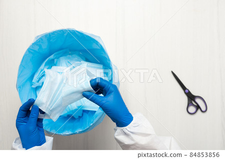 Hands with scissors cut through the medical mask 84853856