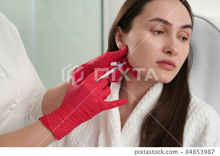 Cosmetologist makes lipolytic injections to burn fat on the chin against double chin. Female aesthetic cosmetology in a beauty salon. Cosmetology concept Cosmetologist makes lipolytic injections to burn fat on the chin against double chin. Female aesthetic cosmetology in a beauty salon. Cosmetology concept 84853987
