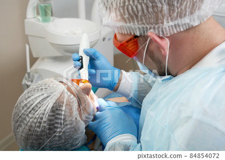 Dentist doing procedure with dental curing UV light in clinic Dentist doing procedure with dental curing UV light in clinic 84854072