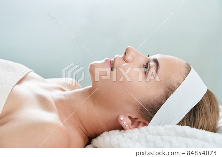 Closeup of relaxed young woman laying on table in spa center. Relaxing massage and body care procedure. Wellness health and beauty concept 84854073