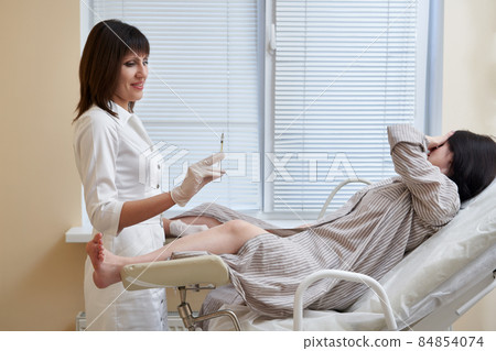 Gynecologist with syringe makes an injection to patient in gynecology chair Gynecologist with syringe makes an injection to patient in gynecology chair 84854074