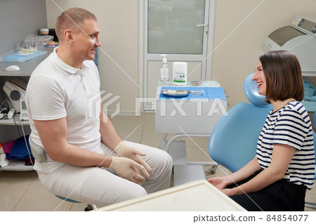 Dentist consulting patient in his office in modern clinic Dentist consulting patient in his office in modern clinic 84854077