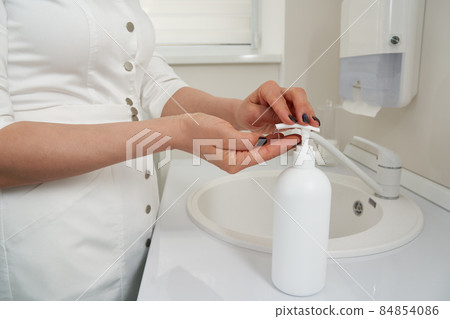 Cropped view of female hands pressing on soap bottle before washing hands in a sink Cropped view of female hands pressing on soap bottle before washing hands in a sink 84854086