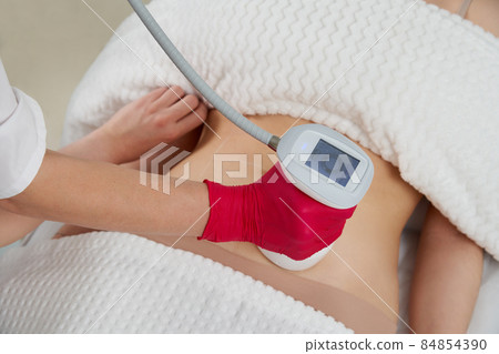 professional cosmetologist performing radiofrequency lifting procedure on the stomach of a woman professional cosmetologist performing radiofrequency lifting procedure on the stomach of a woman 84854390