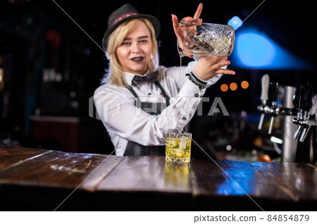 Girl barman concocts a cocktail behind the bar Girl barman concocts a cocktail behind the bar 84854879