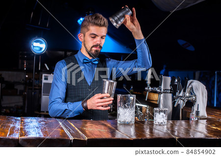 Expert Female bartender pouring fresh alcoholic drink into the glasses in the nightclub 84854902