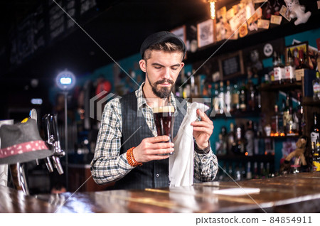 Expert bartender adds ingredients to a cocktail at the bar counter Expert bartender adds ingredients to a cocktail at the bar counter 84854911