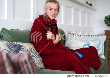 A woman with a cold sits on the sofa at home A woman with a cold sits on the sofa at home 84856064