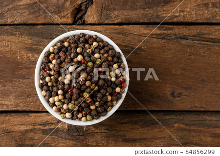 Mixed peppercorns in bowl on rustic wooden table. Top view Mixed peppercorns in bowl on rustic wooden table. Top view 84856299