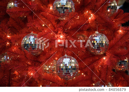 An unusual red Christmas tree. The Christmas tree is decorated with disco balls. Concept of style. Trend. Courage and eccentricity. 84856879