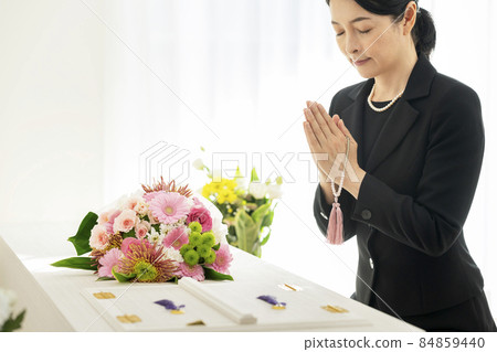 Funeral image Middle woman in mourning holding beads in front of the casket Funeral image Middle woman in mourning holding beads in front of the casket 84859440