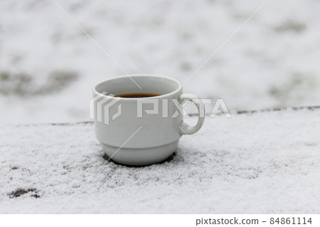Cup of coffee on a snow covered table at winter 84861114