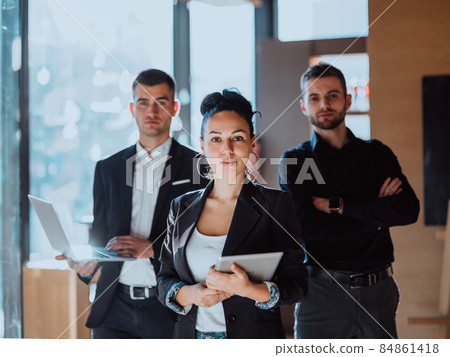 A portrait of a group of entrepreneurs in a modern office holding modern work equipment. 84861418