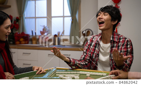 excited son clothing shouting with finger pointing and cheering punching air with fist for winning mahjong game and asking money with beckoning gestures at home during spring festival 84862042