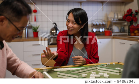 mother winning by self draw smiling with embarrassment as she fails to lay her complete set on table while playing mahjong in the evening at home during spring festival mother winning by self draw smiling with embarrassment as she fails to lay her complete set on table while playing mahjong in the evening at home during spring festival 84862043