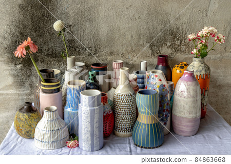 Bouquet of flowers in Handmade Assorted Many Different Ceramic Vases on Calico textured table cloth with old cement wall. Bouquet of flowers in Handmade Assorted Many Different Ceramic Vases on Calico textured table cloth with old cement wall. 84863668
