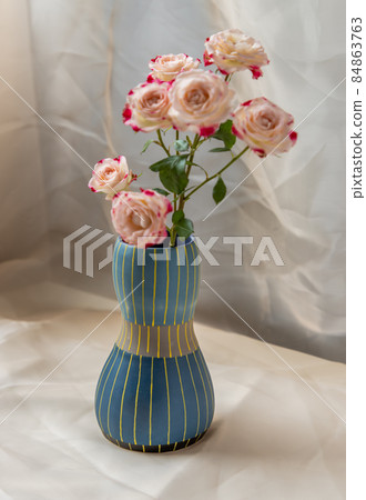 Bouquet of flower in Blue handmade ceramic vase on Blush textured table cloth. Bouquet of flower in Blue handmade ceramic vase on Blush textured table cloth. 84863763