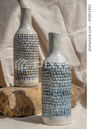 Two white and blue handmade ceramic vases on white textured table cloth. 84863901