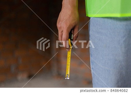 engineer concept The man wearing light shade of jeans standing in the constructing building and handing a tape rule 84864082