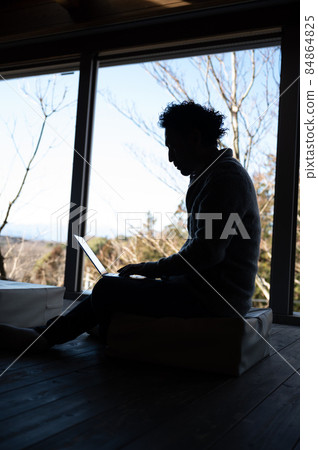 Silhouette of a sideways man doing remote work on a computer There is a copy space Vertically up Silhouette of a sideways man doing remote work on a computer There is a copy space Vertically up 84864825