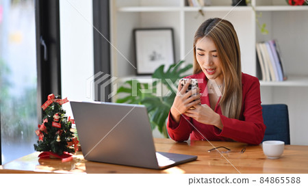 Confident businesswoman sitting in office and having video call on smart phone. Confident businesswoman sitting in office and having video call on smart phone. 84865588