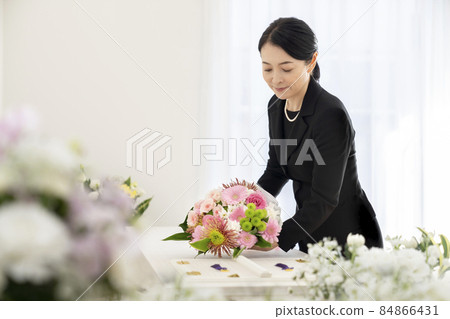 Middle-aged woman offering a casket bouquet Middle-aged woman offering a casket bouquet 84866431