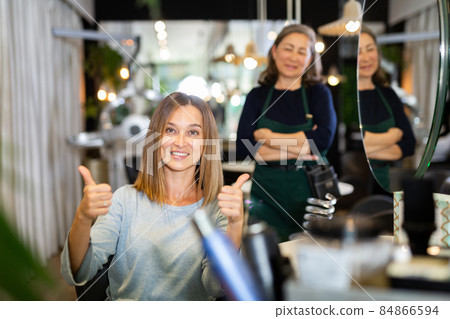 Young woman giving thumbs up happy with hairdo in hairdressing salon 84866594