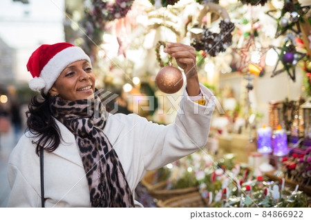Woman choosing christmas decorations at fair Woman choosing christmas decorations at fair 84866922